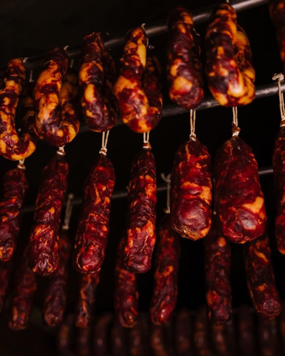 Enchidos pendurados em varas no fumeiro